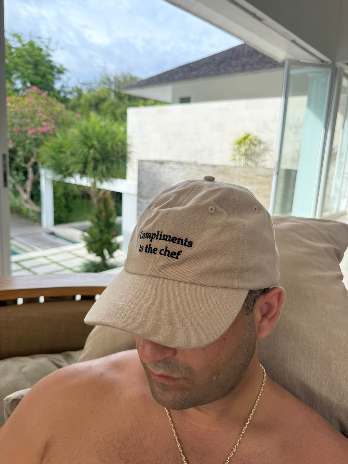 Man wearing the beige Compliments to the chef embroidered cap on a poolside terrace - No Hat No Play